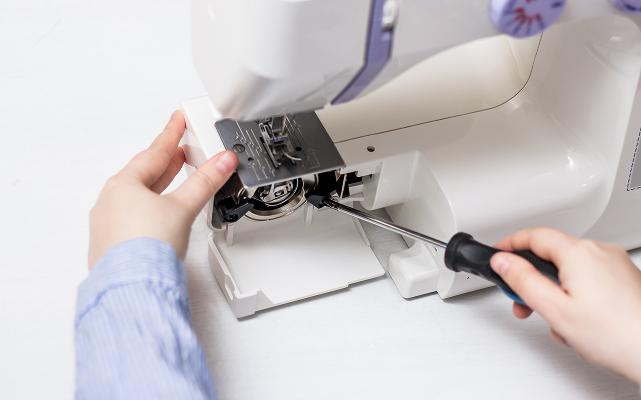 Technician performing sewing machine repair on a vintage unit.